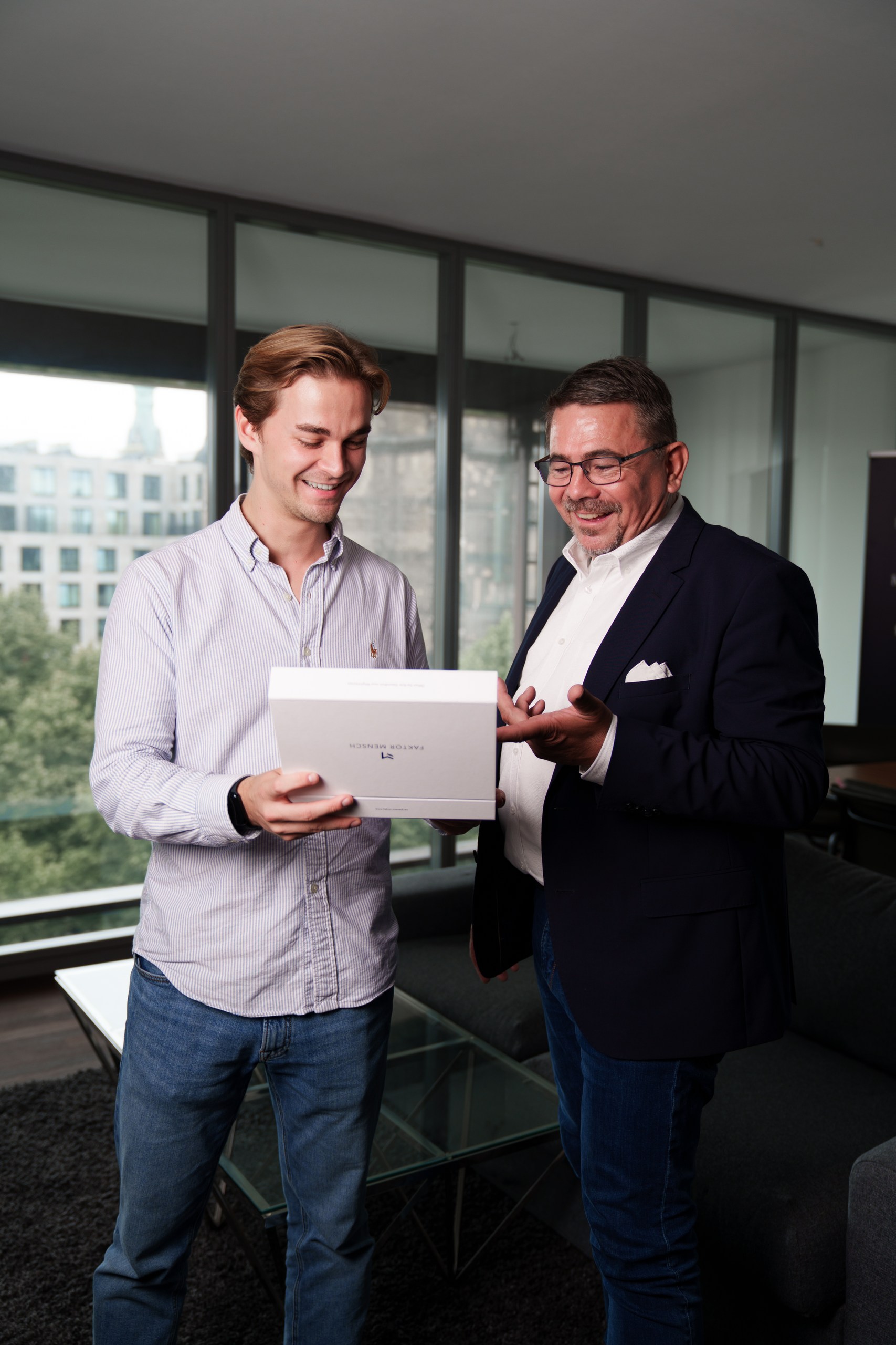 Zwei Mitarbeiter von FAKTOR MENSCH betrachten eine FAKTOR MENSCH Willkommensbox